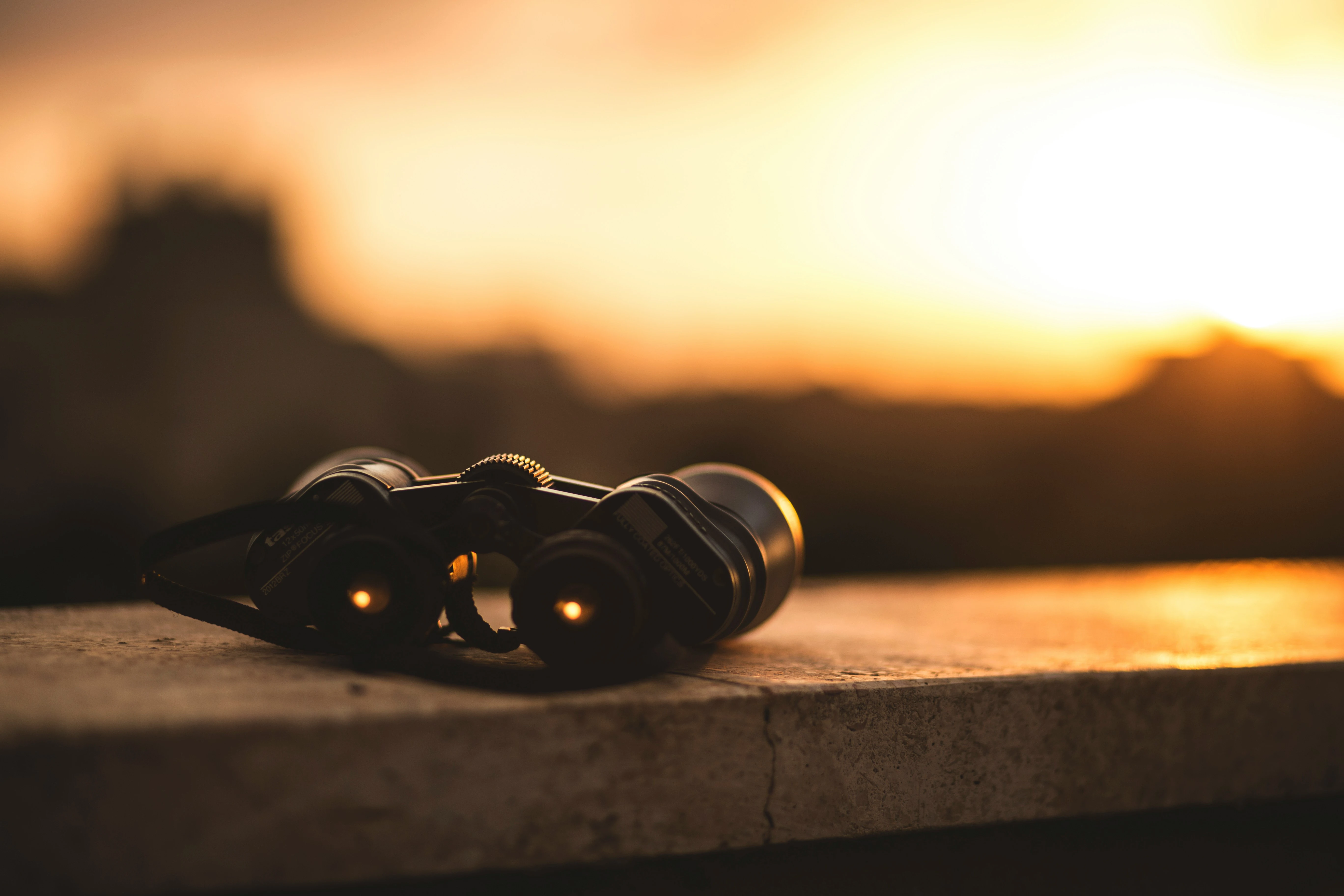 Ein Fernglas liegt bei Sonnenaufgang auf einer Mauer